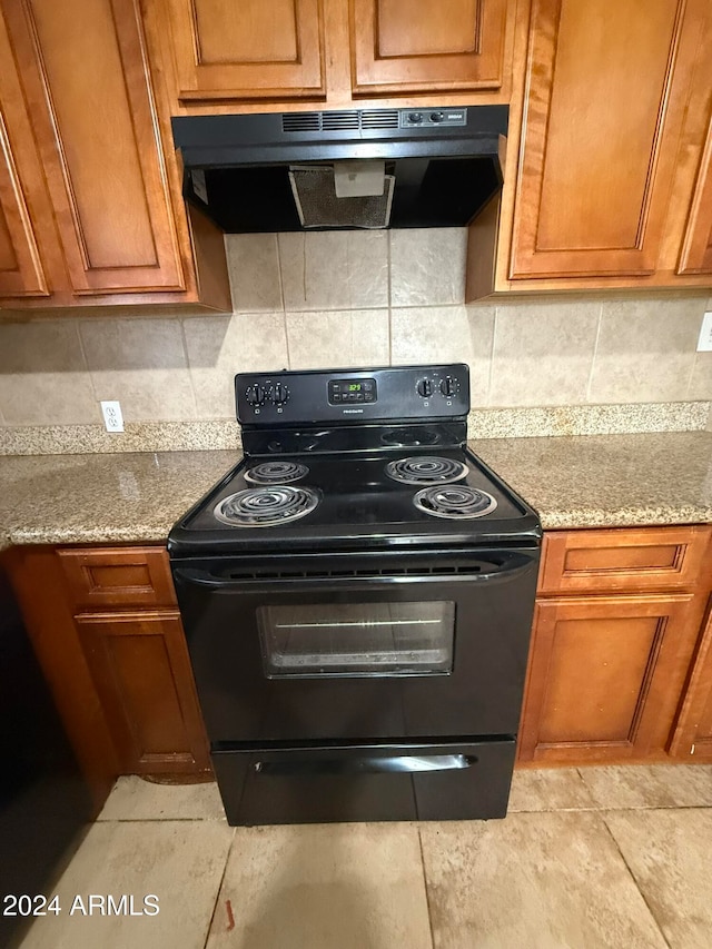 kitchen with backsplash, light stone countertops, and black range with electric cooktop