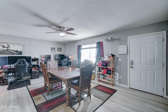 dining space with ceiling fan, baseboards, light wood finished floors, and a textured ceiling