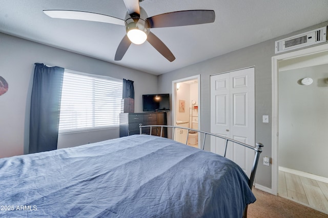 carpeted bedroom featuring visible vents, ensuite bathroom, baseboards, and a ceiling fan