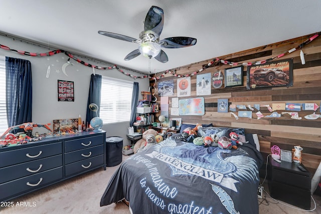 carpeted bedroom featuring wooden walls and a ceiling fan