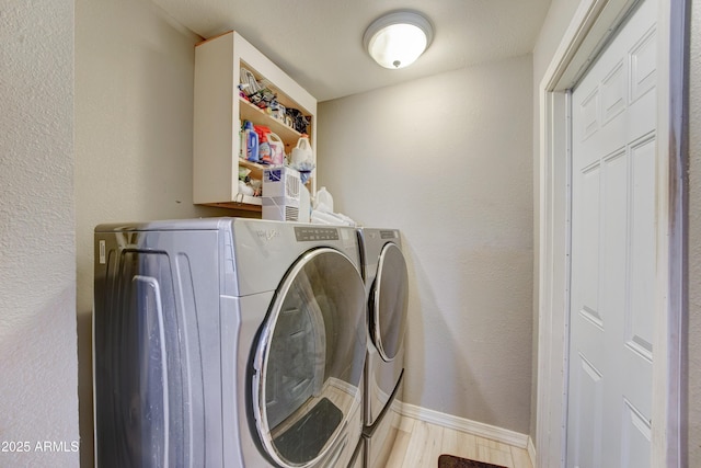 laundry area with washing machine and clothes dryer, baseboards, wood finished floors, laundry area, and a textured wall