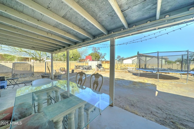 view of patio featuring outdoor dining area, a fenced backyard, and a trampoline