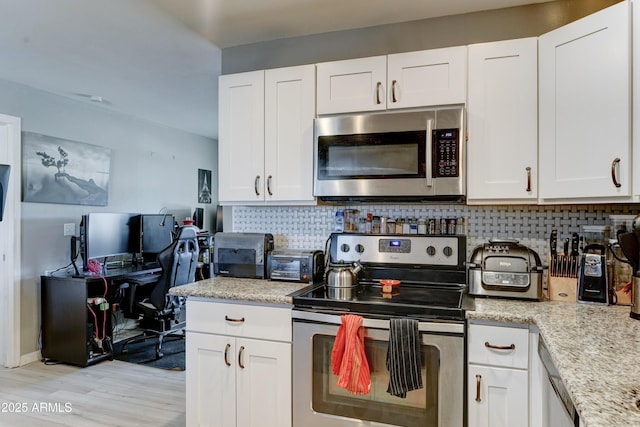 kitchen with light wood-type flooring, tasteful backsplash, appliances with stainless steel finishes, white cabinets, and light stone countertops