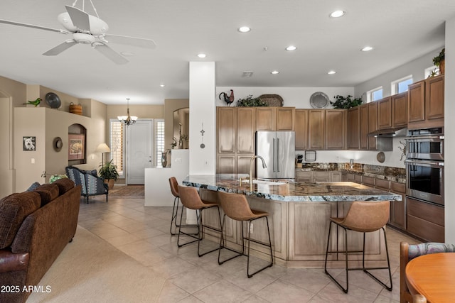 kitchen with decorative light fixtures, a kitchen bar, a healthy amount of sunlight, appliances with stainless steel finishes, and light tile patterned floors