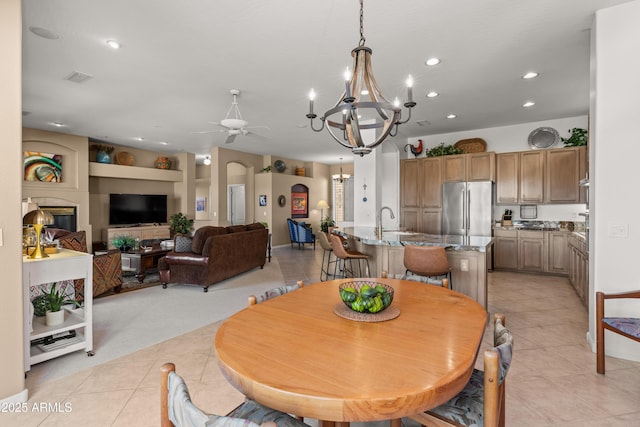 tiled dining room with built in shelves, sink, and ceiling fan with notable chandelier