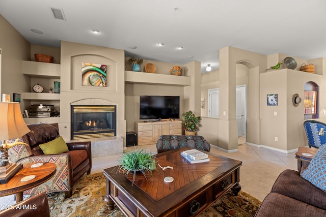 living room with built in shelves, a fireplace, and light tile patterned floors