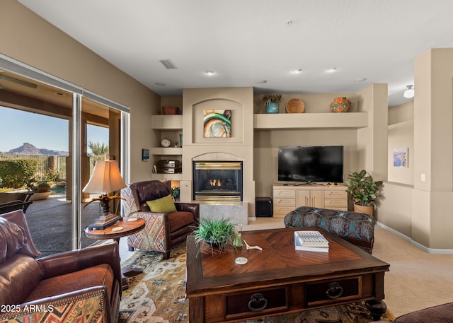 living room with built in features, a tiled fireplace, and carpet floors