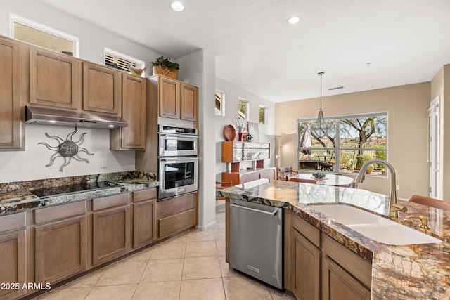 kitchen featuring decorative light fixtures, dark stone countertops, sink, light tile patterned flooring, and appliances with stainless steel finishes