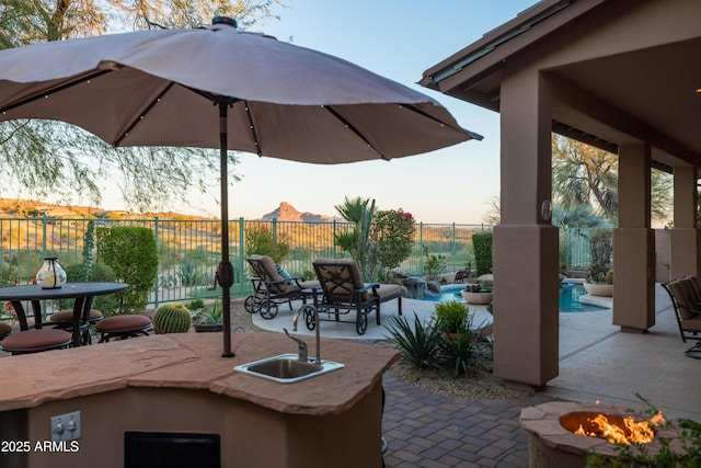 patio terrace at dusk featuring a mountain view, a fire pit, and a wet bar