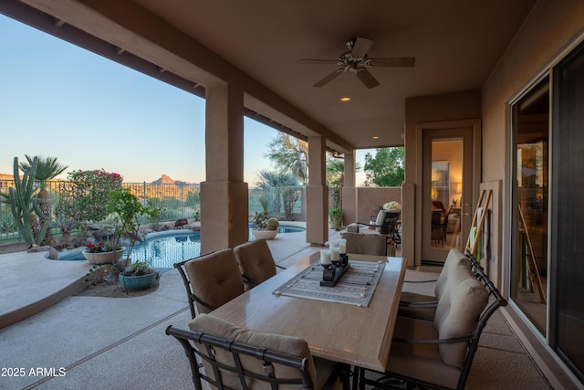 patio terrace at dusk featuring a fenced in pool and ceiling fan