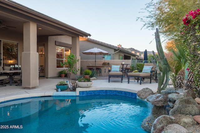 view of swimming pool with ceiling fan, exterior bar, and a patio area