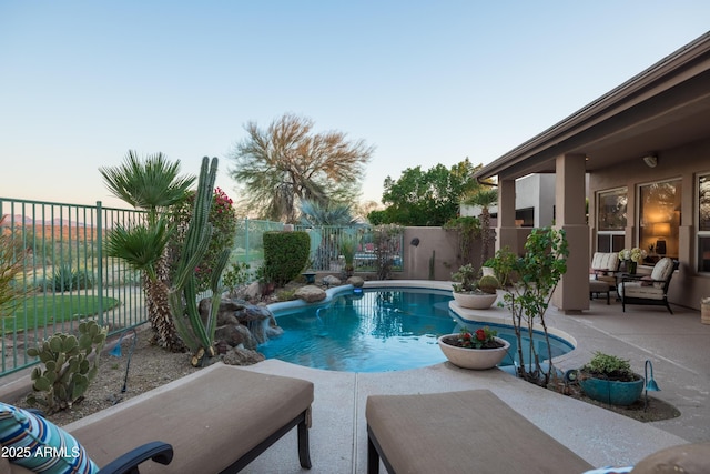 pool at dusk featuring pool water feature and a patio area