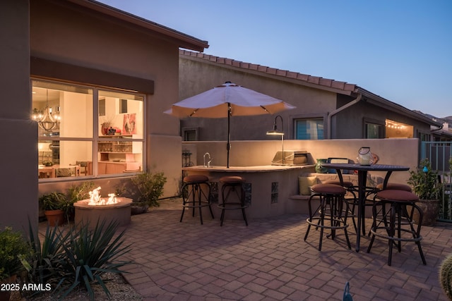 patio terrace at dusk with a wet bar and area for grilling