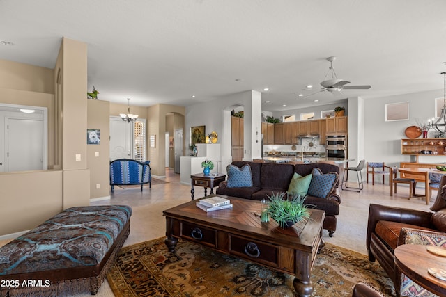 living room featuring light tile patterned flooring and ceiling fan with notable chandelier