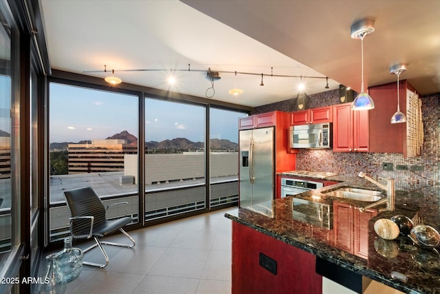 kitchen with kitchen peninsula, sink, a mountain view, appliances with stainless steel finishes, and pendant lighting