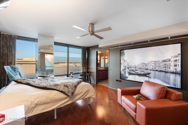 bedroom featuring a wall of windows, hardwood / wood-style floors, a water view, and ceiling fan