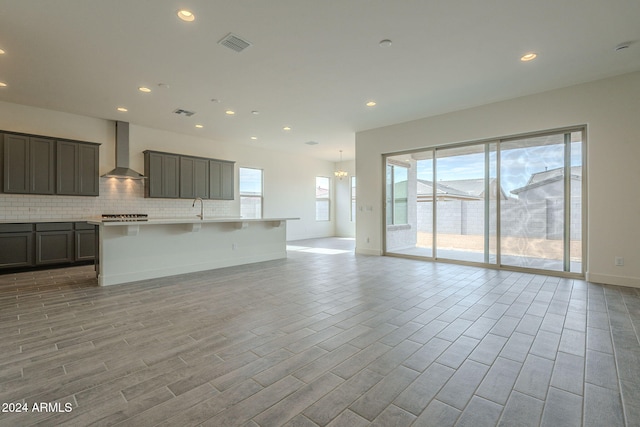 unfurnished living room with light wood-type flooring, an inviting chandelier, and sink