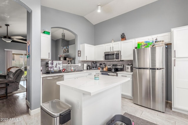 kitchen with sink, appliances with stainless steel finishes, backsplash, a center island, and white cabinets