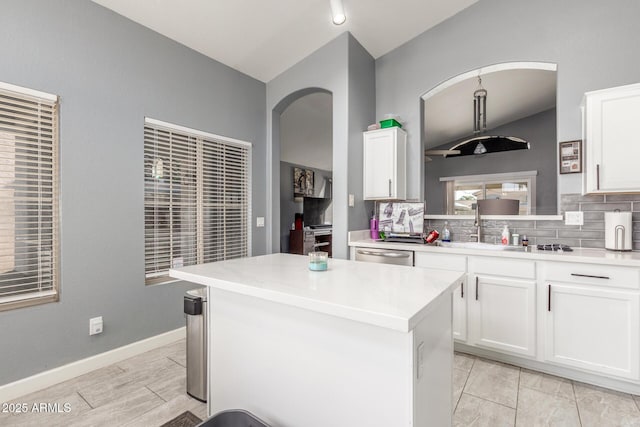 kitchen featuring white cabinetry, tasteful backsplash, stainless steel dishwasher, and a kitchen island