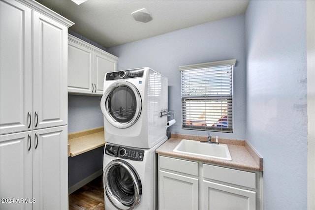 laundry room featuring stacked washer / drying machine, dark hardwood / wood-style floors, sink, and cabinets