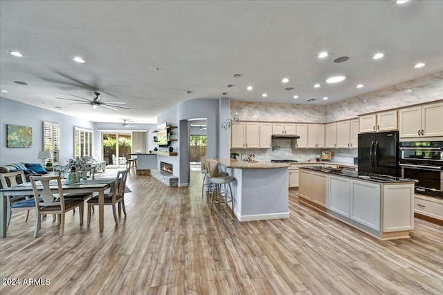 kitchen with ceiling fan, a center island, black appliances, and light wood-type flooring