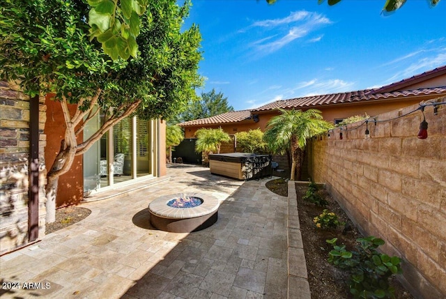 view of patio / terrace with a fire pit and a hot tub