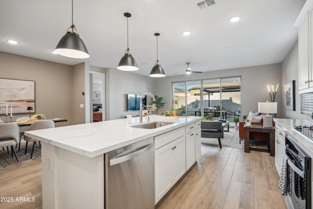 kitchen featuring white cabinets, dishwasher, sink, and a kitchen island with sink