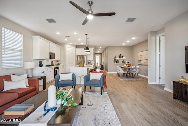 living room featuring ceiling fan and light hardwood / wood-style flooring