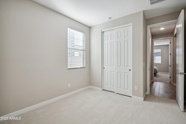 unfurnished bedroom featuring light carpet and a closet