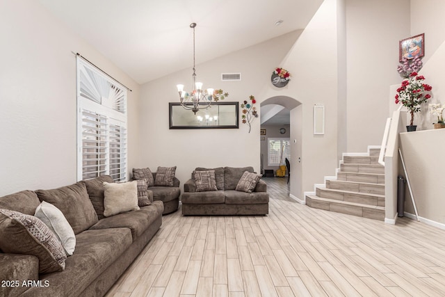 living area with arched walkways, visible vents, light wood-style floors, a chandelier, and stairs