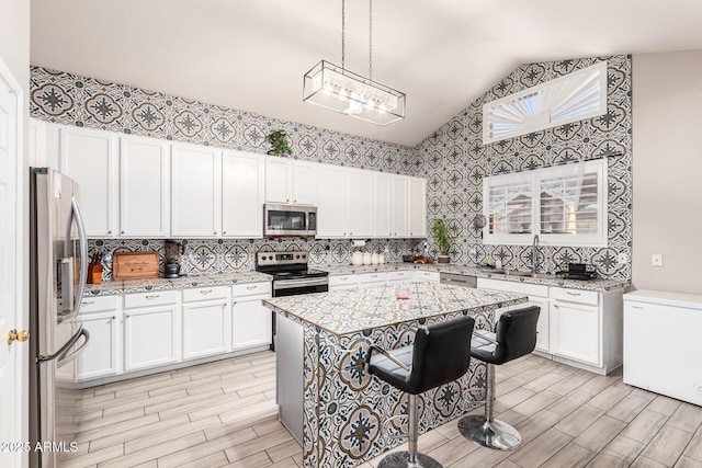 kitchen with stainless steel appliances, white cabinets, and light stone counters