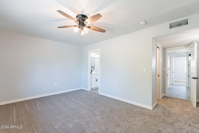 carpeted spare room featuring brick wall and ceiling fan