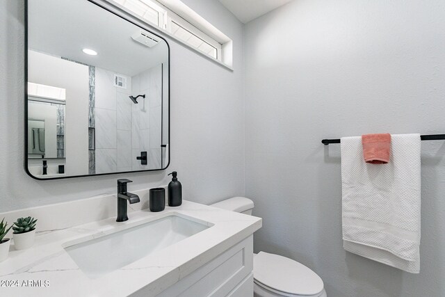 bathroom with vanity, toilet, and a tile shower