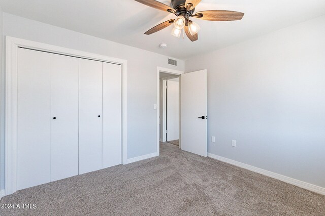 unfurnished bedroom with light colored carpet, ceiling fan, and a closet