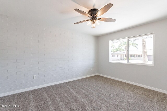 unfurnished room with brick wall, ceiling fan, and carpet floors