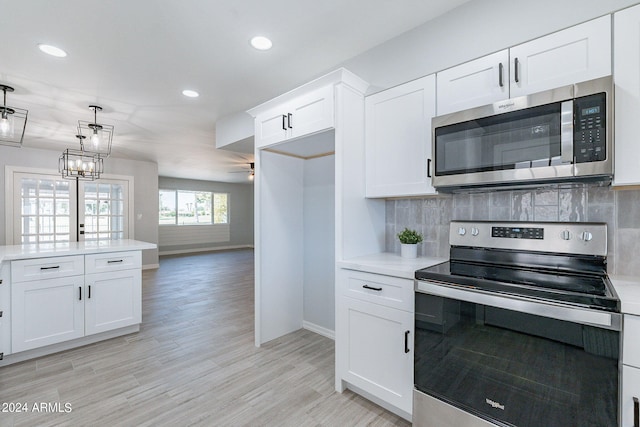 kitchen with white cabinets, decorative light fixtures, stainless steel appliances, light hardwood / wood-style floors, and decorative backsplash