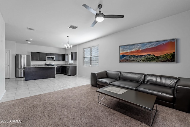 carpeted living room with sink and ceiling fan with notable chandelier