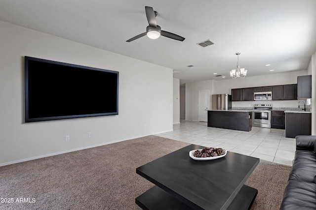 tiled living room featuring sink and ceiling fan with notable chandelier