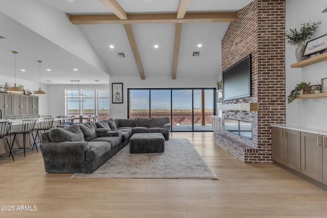 living room with beam ceiling, a large fireplace, and light wood-type flooring