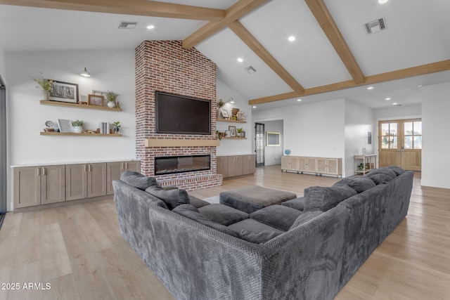 living room with beamed ceiling, a brick fireplace, high vaulted ceiling, and light hardwood / wood-style flooring