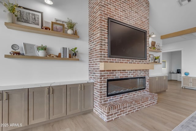 living room featuring a fireplace, vaulted ceiling, and light hardwood / wood-style flooring