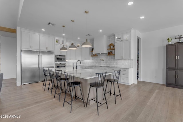 kitchen featuring stainless steel appliances, custom exhaust hood, white cabinets, and a spacious island