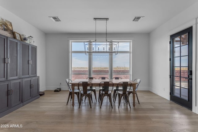 dining area featuring a healthy amount of sunlight, a chandelier, and light wood-type flooring