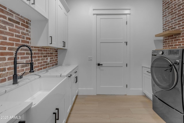 laundry area featuring cabinets, washer / clothes dryer, sink, and light hardwood / wood-style flooring