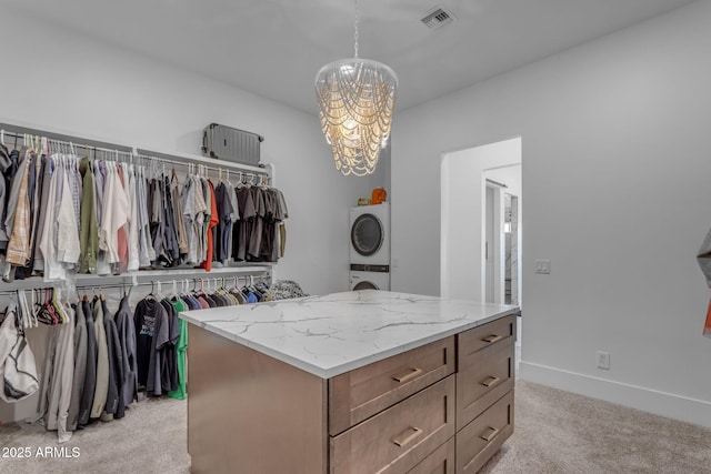 walk in closet with stacked washer / dryer, light colored carpet, and a notable chandelier