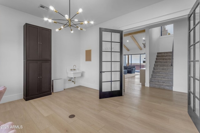 interior space featuring sink, french doors, a chandelier, and light wood-type flooring