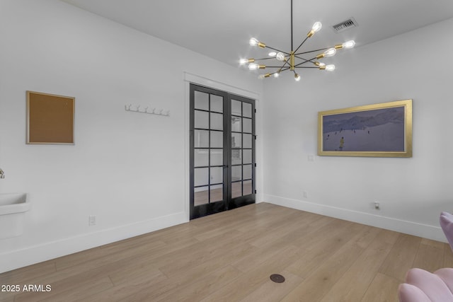 unfurnished room with french doors, an inviting chandelier, and hardwood / wood-style floors