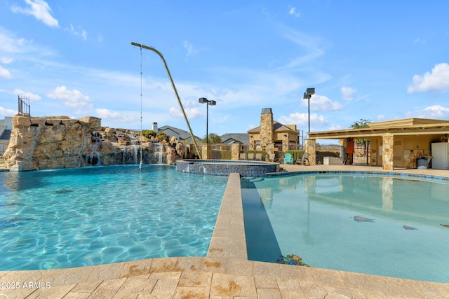 view of swimming pool with pool water feature and an in ground hot tub