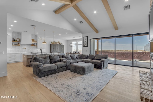 living room with beam ceiling, high vaulted ceiling, and light wood-type flooring