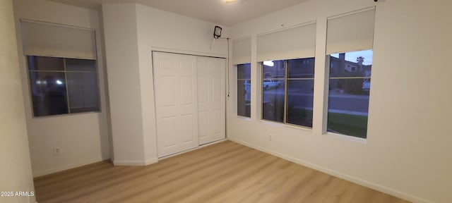 unfurnished bedroom featuring a closet, baseboards, and wood finished floors